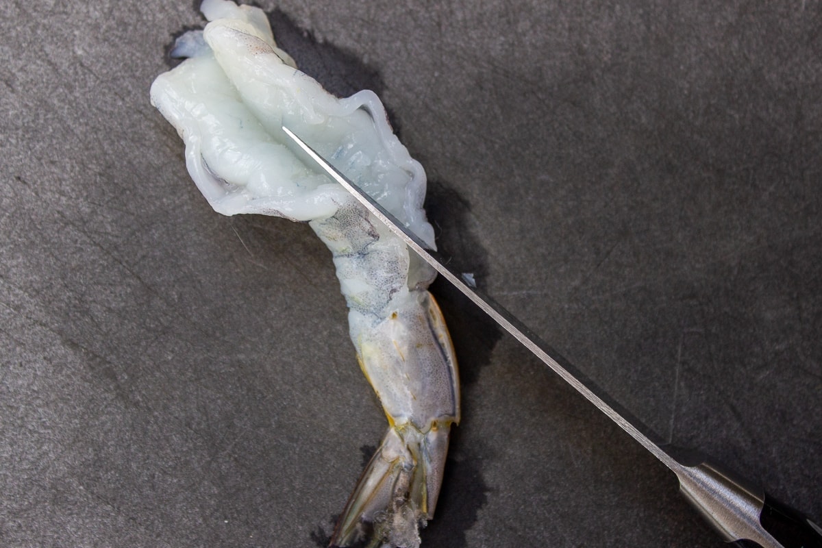 knife slicing into top of shrimp