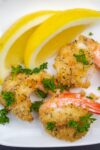 3 breaded butterflied shrimp on plate with lemon p