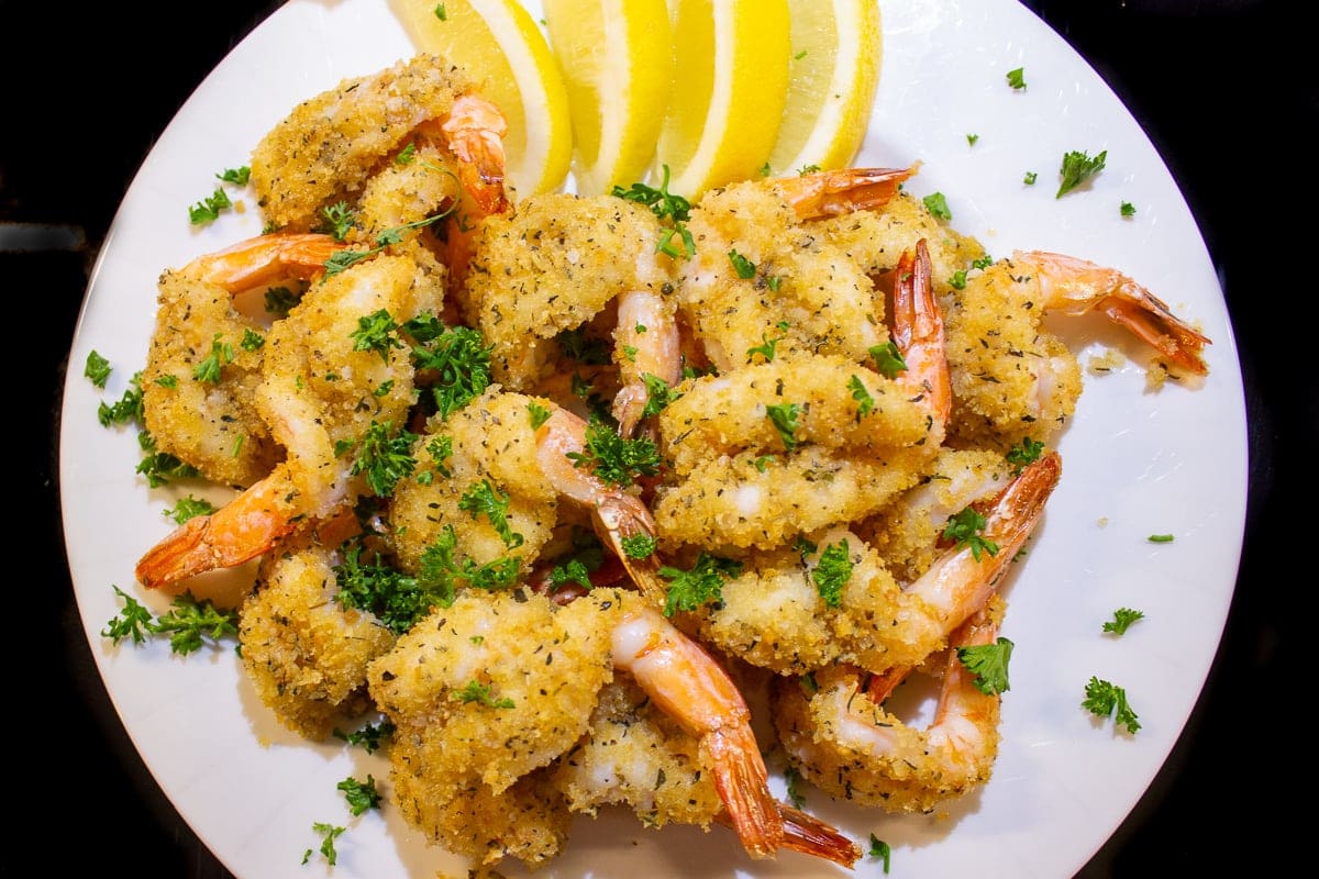 pile of breaded baked butterflied shrimp on plate