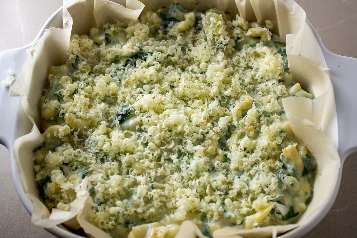 spinach mac and cheese in casserole dish with cheese on top unbaked