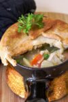 individual chicken pot pie partially cut open to see chicken vegetables and gravy inside p