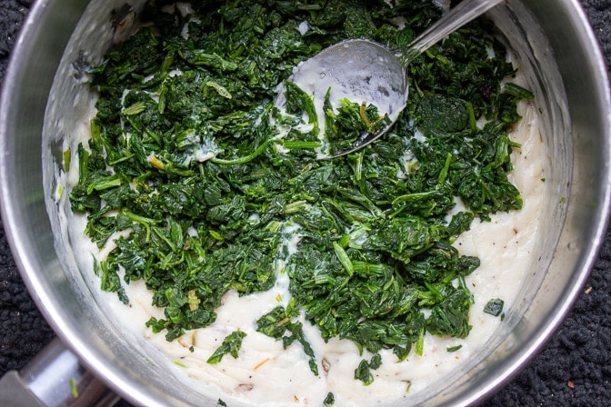 Spinach added to cream sauce in a pot