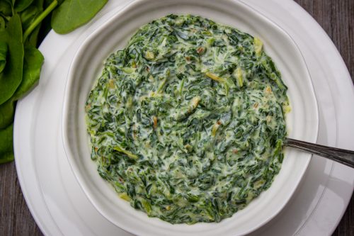 Creamed Spinach in a serving bowl sitting on a plate f