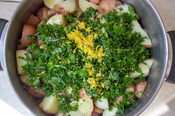 herbs, lemon zest and dressing added to boiled potatoes in pot