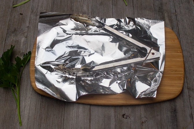 flank steak on cutting board resting covered with tin foil
