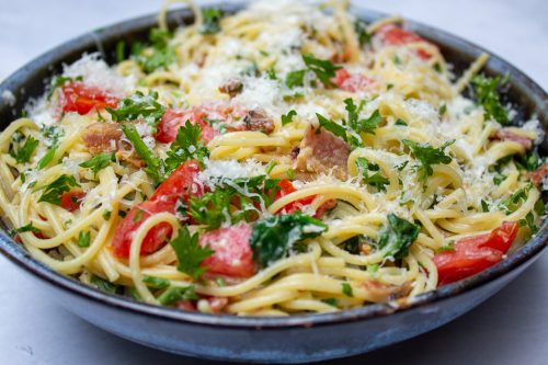 spaghetti carbonara with tomatoes and spinach in bowl