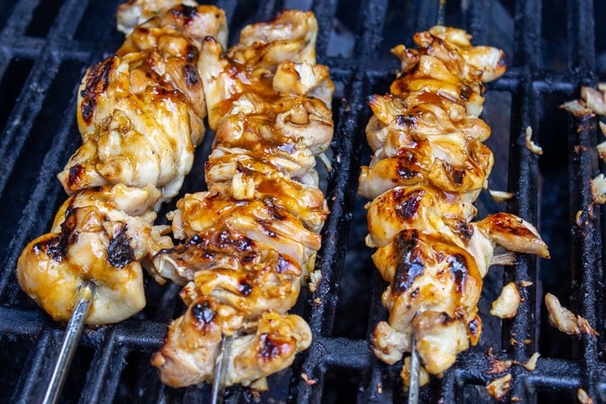 3 chicken skewers on the grill, partly cooked