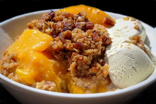 Peach Crumble in a bowl with vanilla ice cream