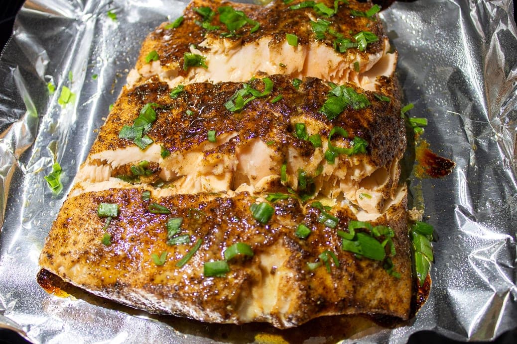 Sweet and Spicy Salmon cut in 3 pieces on pan after roasting, garnished with green onions