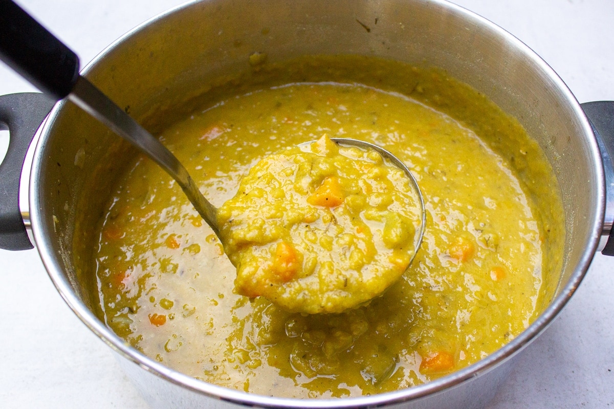 ladle scoop of pea soup over pot