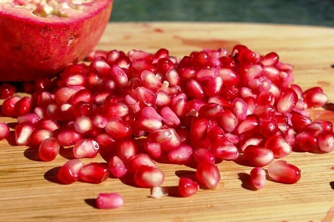 pomegranate seeds on cutting board.