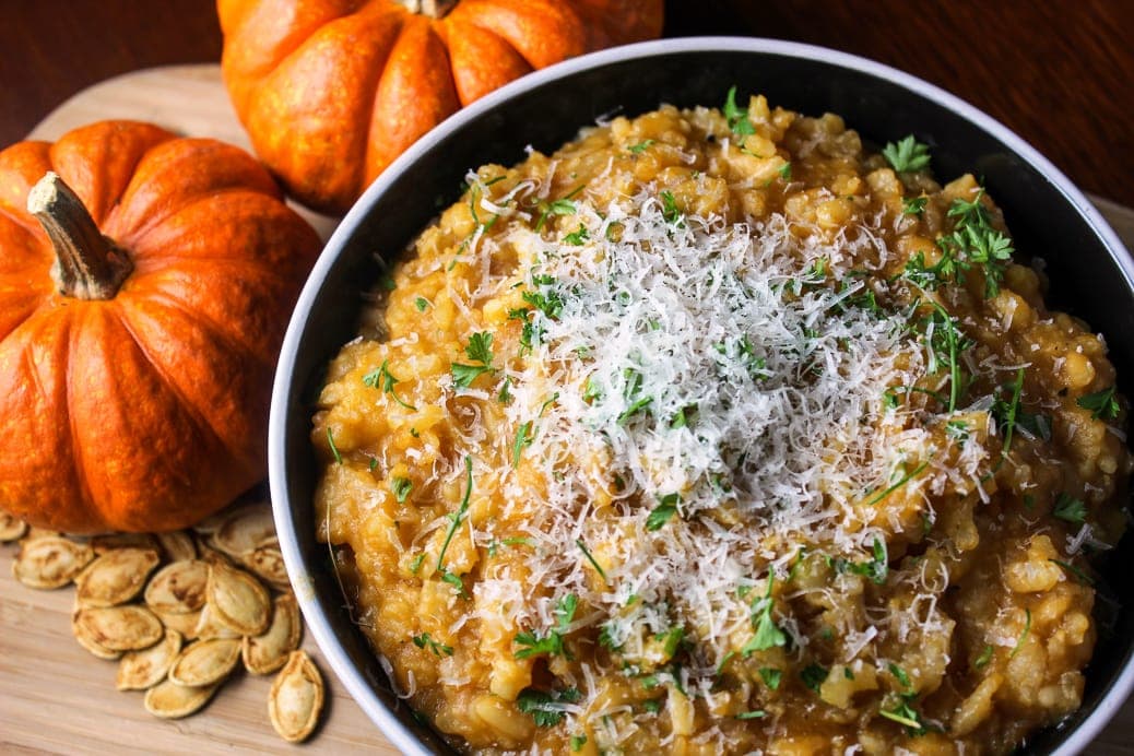 Slow Cooker Pumpkin Risotto in blow on board with baby pumpkins and pumpkin seeds