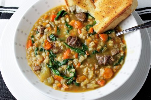 beef barley vegetable soup in a bowl with toasted bread for dipping