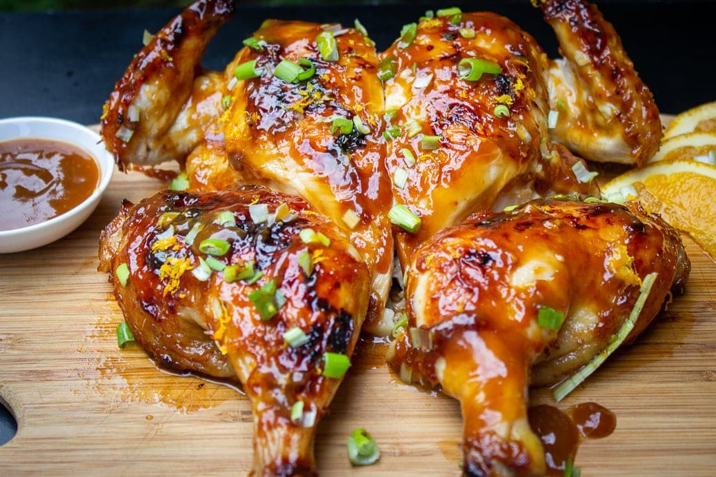 Spatchcock Roast Chicken with Teriyaki Glaze on cutting board with green onion garnish