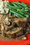 meatloaf with mushroom gravy on red plate with mashed potatoes and green beans