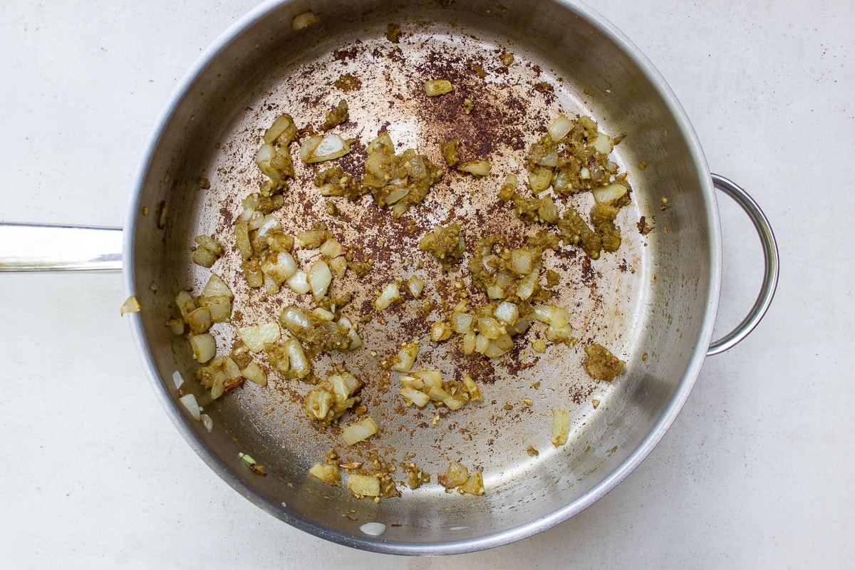 onion, green curry paste and garlic in pan