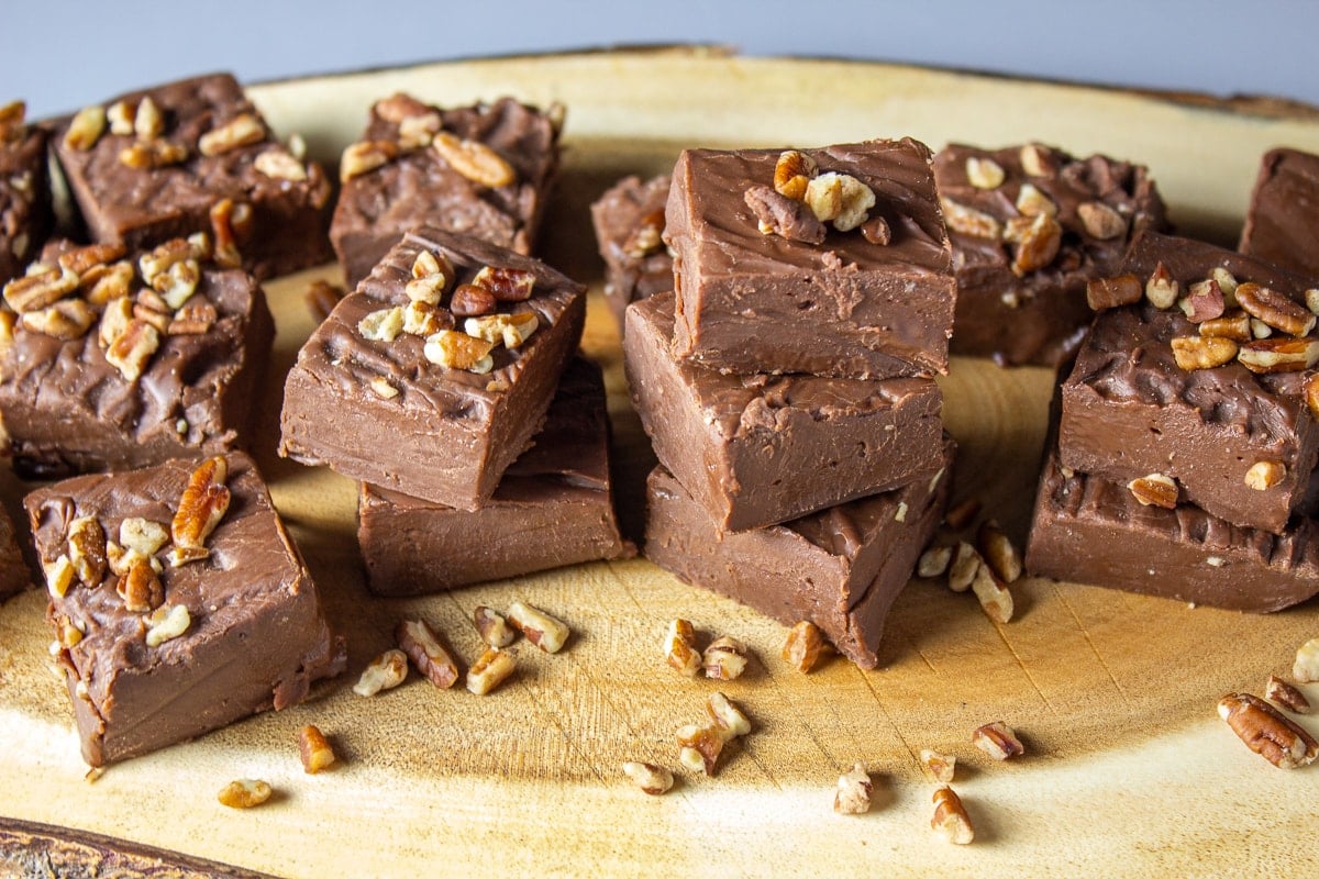 pieces of easy chocolate fudge on serving board with nuts on top