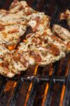 Mediterranean marinated grilled chicken on the grill with hot flames underneath p