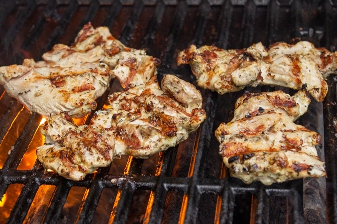 Mediterranean marinated grilled chicken on the grill with hot flames underneath