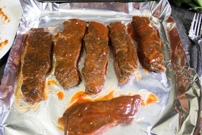 boneless beef short ribs on plate with bbq sauce brushed on