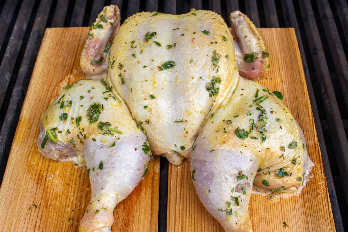 uncooked spatchcock chicken on planks on grill