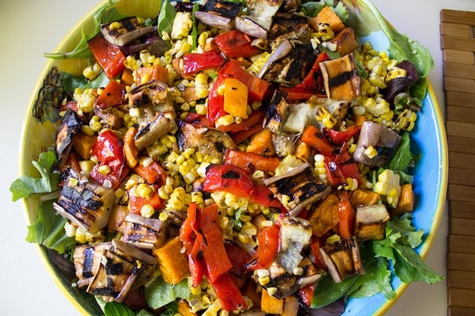 grilled corn, peppers, onion, eggplant on top of salad and quinoa