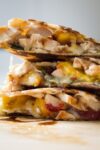 chicken quesadilla with brie and peaches stacked on cutting board