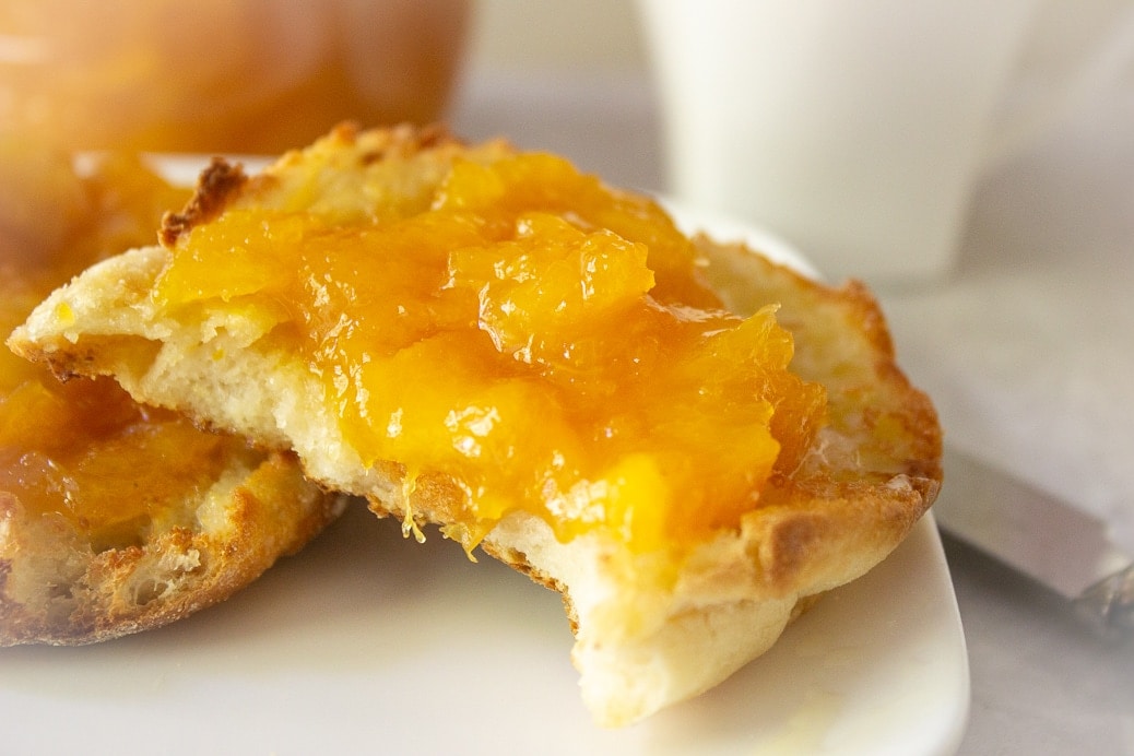 close up of peach marmalade on english muffin on plate 