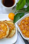 peach marmalade on english muffin on plate with jar of marmalade beside and coffee p2