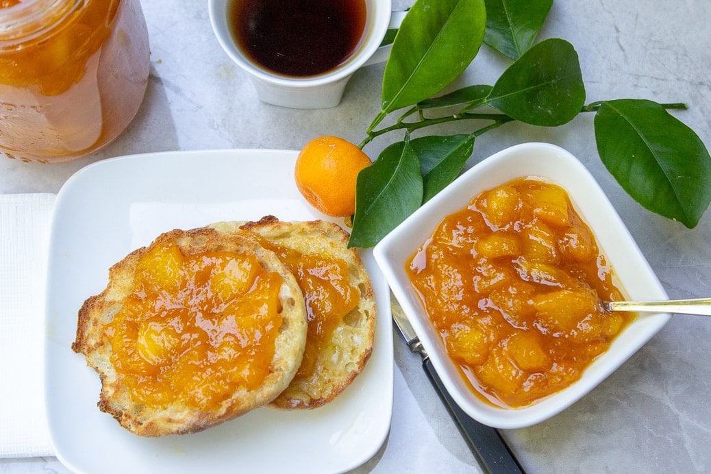 peach marmalade on english muffin on plate with jar of marmalade beside and coffee 3