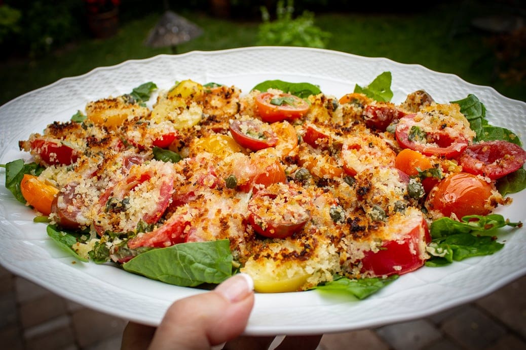 Broiled Cherry Tomatoes with Cheese and Panko Crumbs on a bed of spinach sitting on a plate