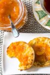 peach marmalade on English muffin with jar of marmalade beside p