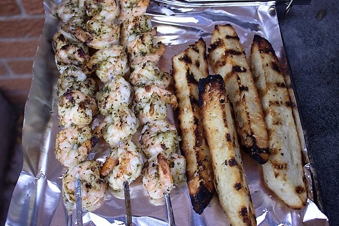 grilled shrimp skewers and bread wedges on pan