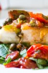 Roasted Halibut with Tomatoes and Capers on bed of spinach on a plate p1