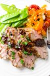 sliced grilled pork tenderloin with balsamic maple mustard glaze on plate with peas and carrot salad p