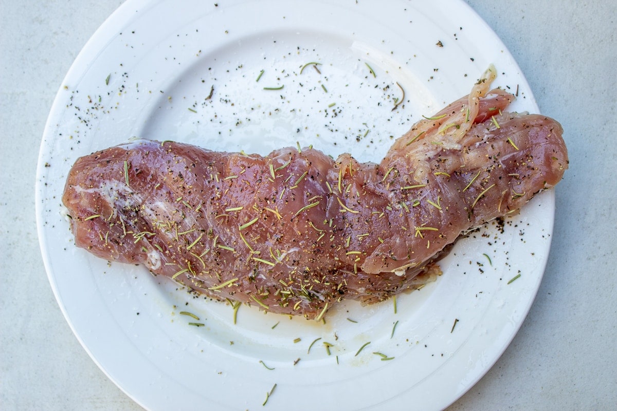 raw seasoned pork tenderloin on plate