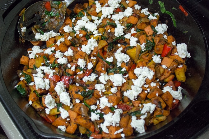 goat cheese sprinkled over sauteed vegetable in pan
