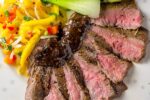 Sous Vide Flank Steak with glaze sliced on plate with mango salad
