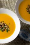 2 bowls of squash sweet potato mandarin soup with nut herb topping