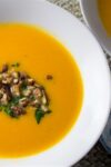 Squash, Sweet Potato & Mandarin Soup in a bowl with roasted pecans as garnish