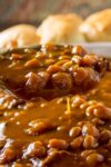 scoop of Instant Pot Baked Beans over the pot of baked beans p