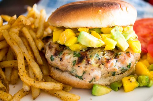 Chicken Burger on bun with Mango-Avocado Salsa on a plate with fries