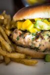 Grilled Chicken Burgers in bun with mango avocado salsa beside french fries p