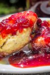 homemade strawberry jam on two scones on a plate p p