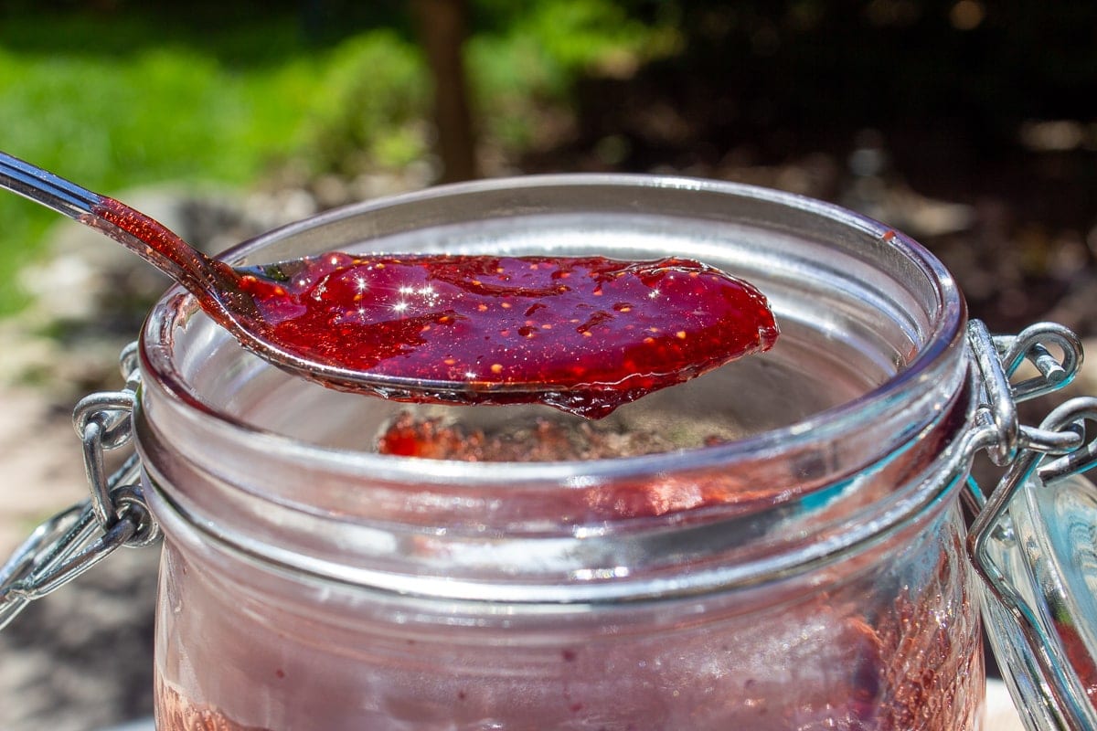 spoon of strawberry jam over a mason jar