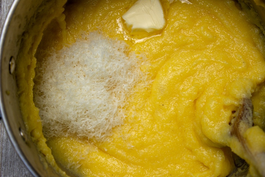 cooked polenta in a pot with butter and cheese added