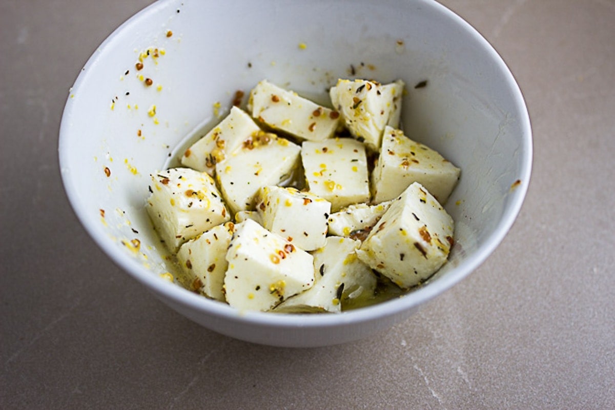 boccocini cut up in bowl in marinade
