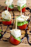 mini caprese skewers on cutting board with balsamic reduction drizzle p