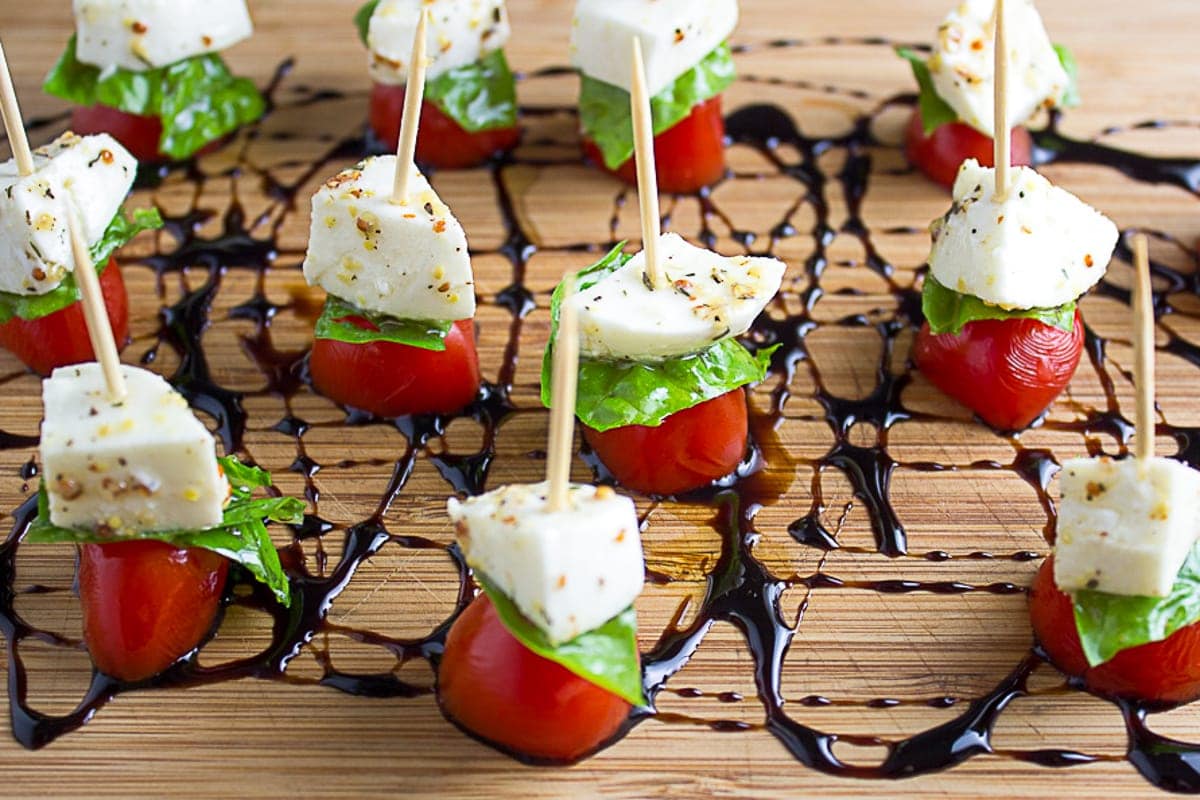 Mini Caprese skewers on cutting board with balsamic reduction drizzle f