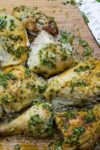 cut up Chicken With Herb Garlic Lemon Smear on cutting board with knife p
